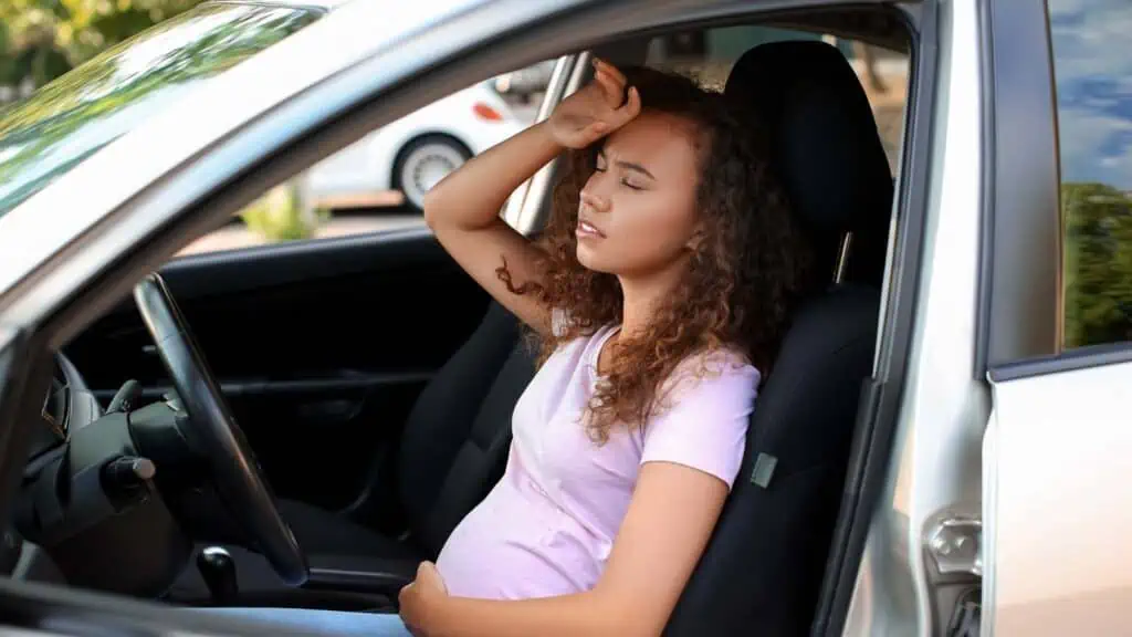 pregnant woman in a car feeling sick, nausea, tired