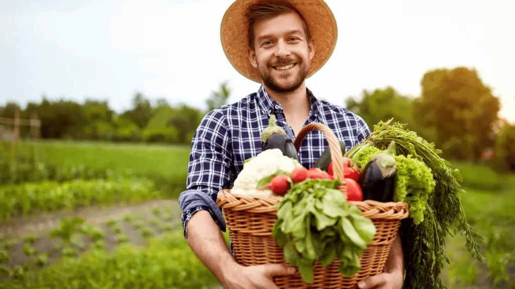 farmer with a basket of vegetables happy hat outside garden