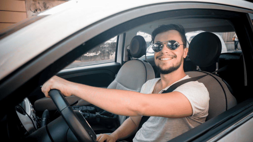man smiling sunglasses driving with one hand happy