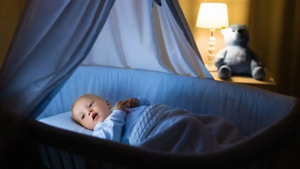 Adorable baby in blue bassinet at night