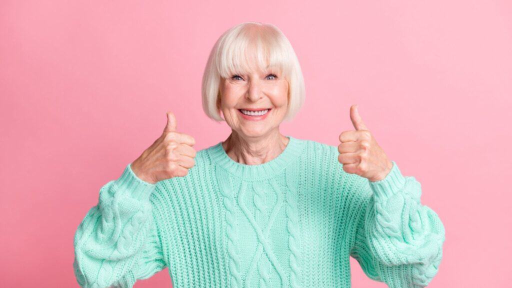 Adorable happy old woman showing thumbs up