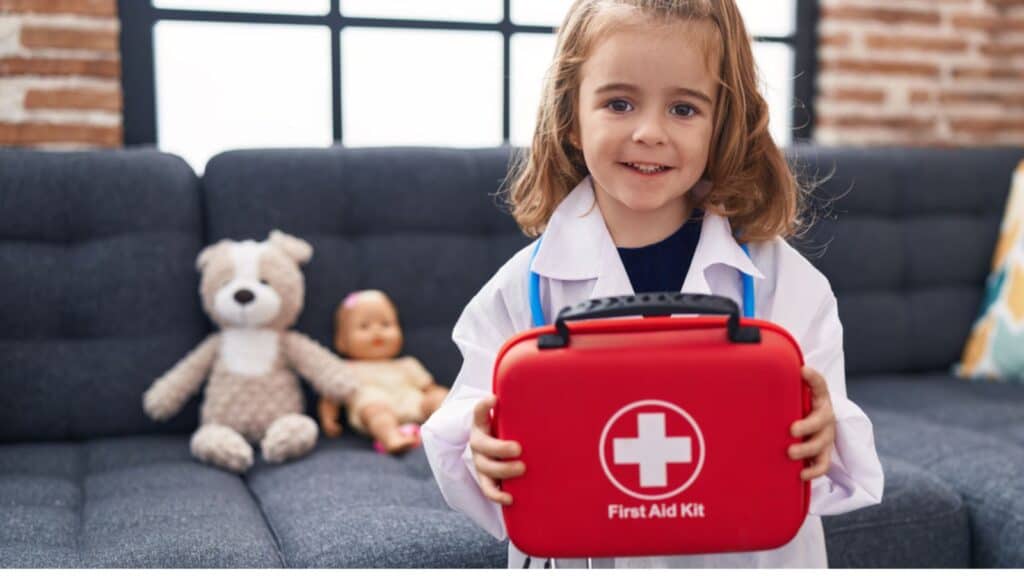 Happy Adorable hispanic girl wearing doctor uniform holding first kit aid at home