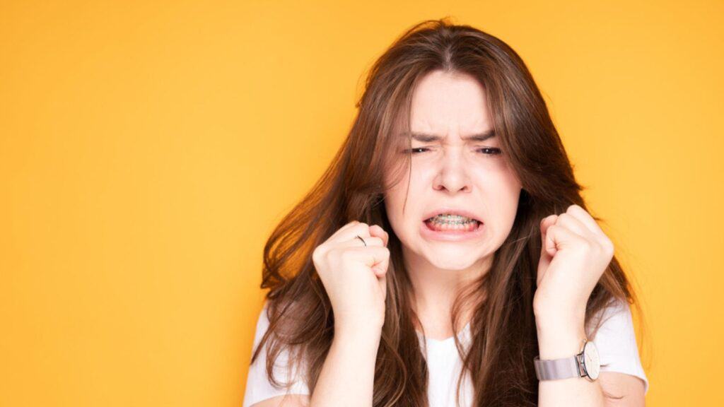 Annoyed woman with braces suffering from dental pain