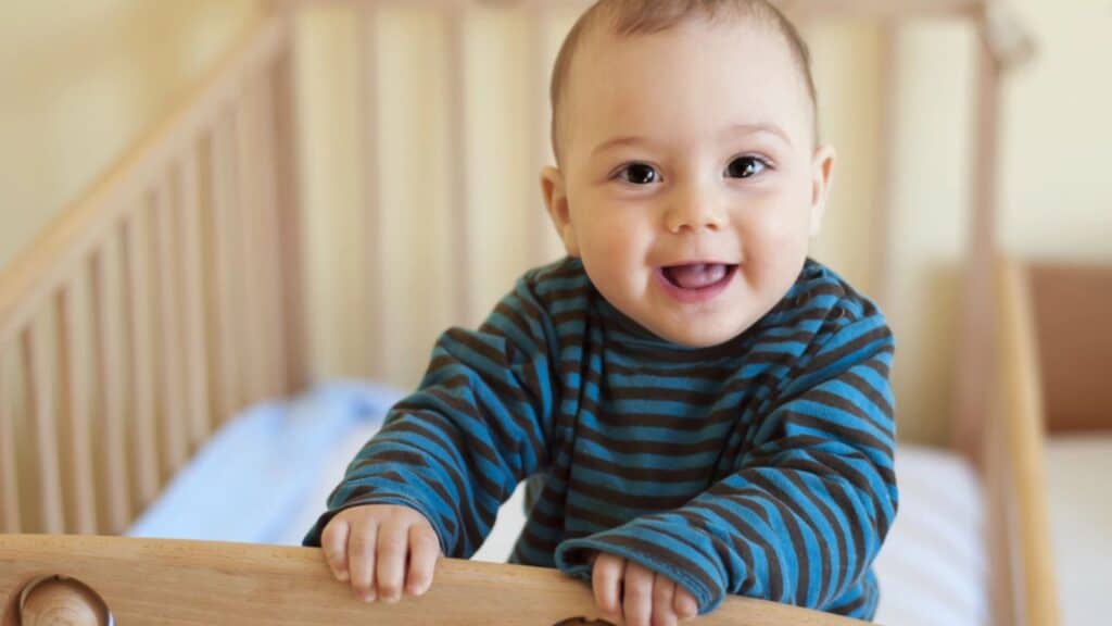 Baby standing in a small bed