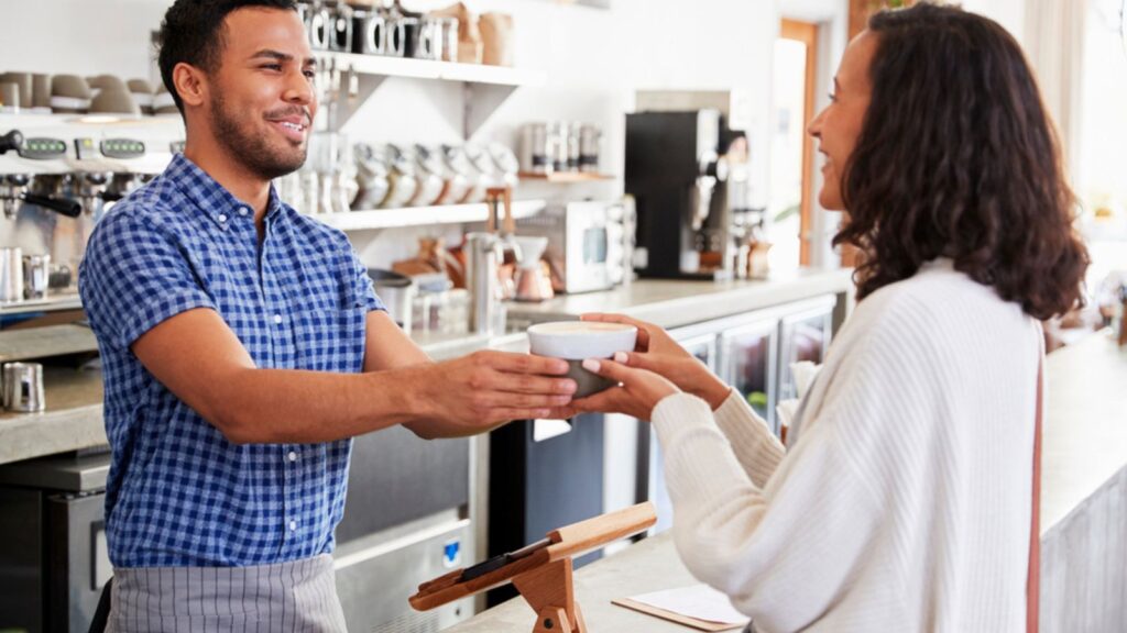 Barista man passing cup of coffee to customer