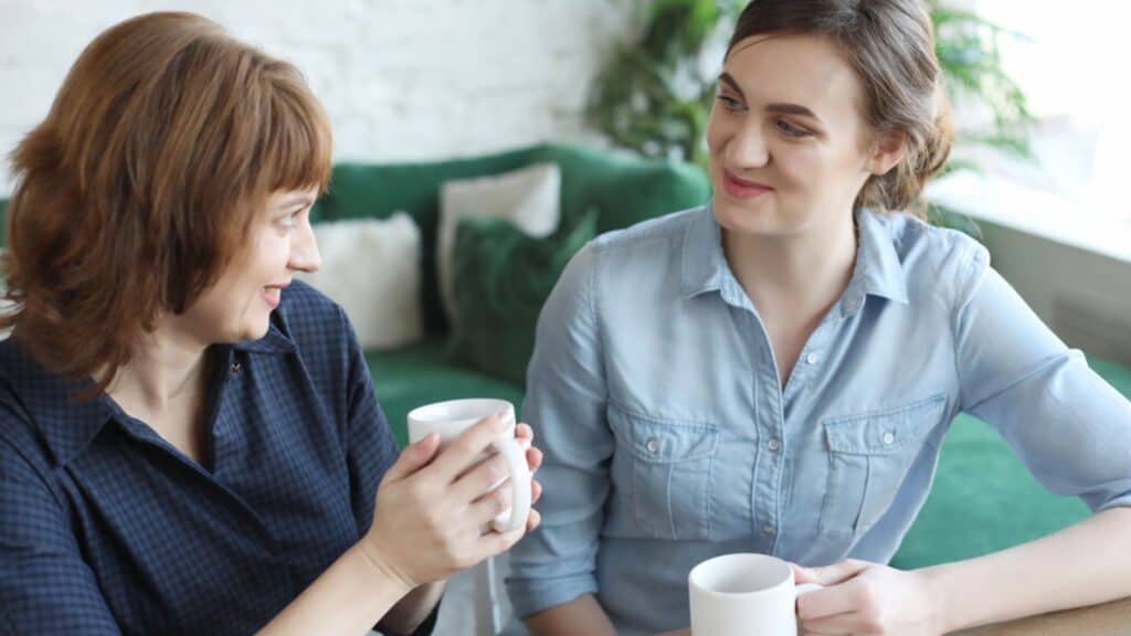Beautiful mature mother and her adult daughter are drinking coffee