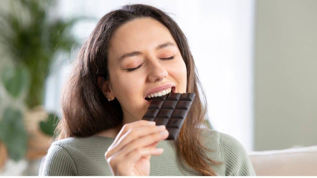 Beautiful young woman biting a bar chocolate bar