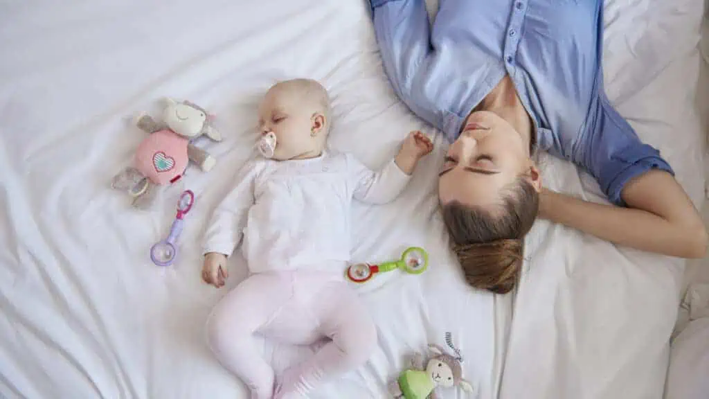 mom and baby sleeping on bed