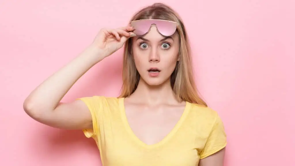 woman raising her sunglasses in shock