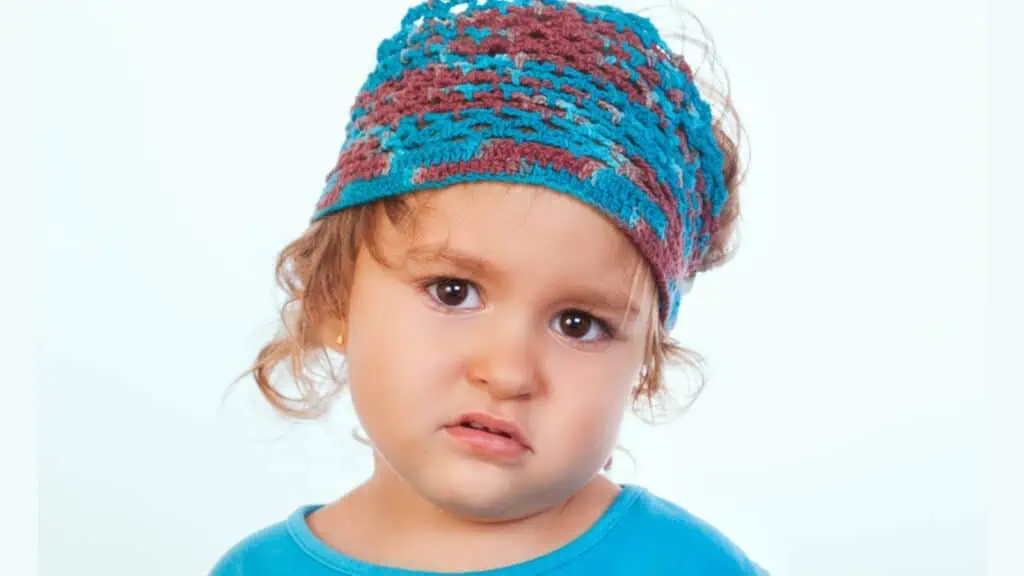 Bored little kid in handmade headband looking at camera