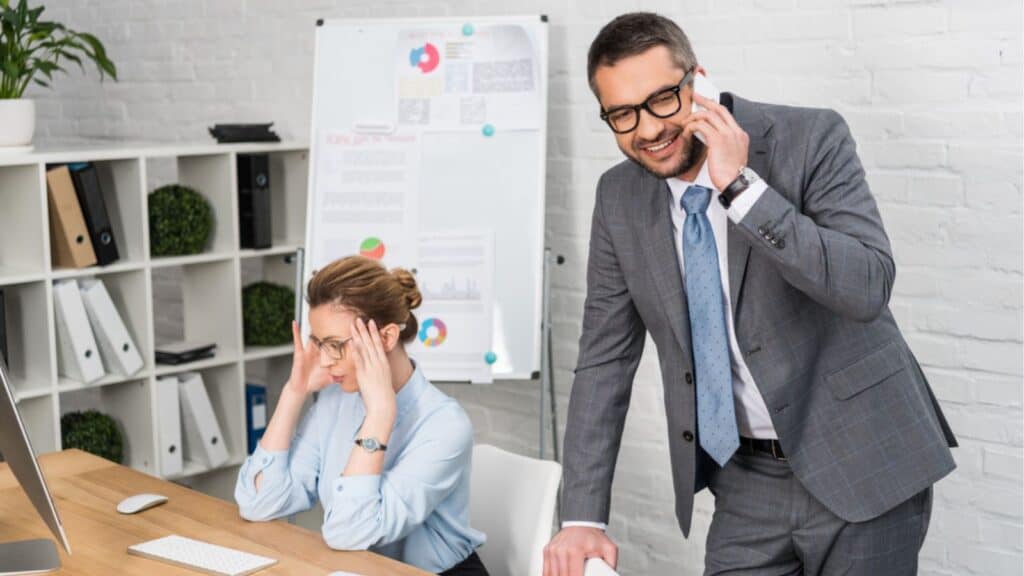Businessman talking by phone while his annoyed colleague trying to work