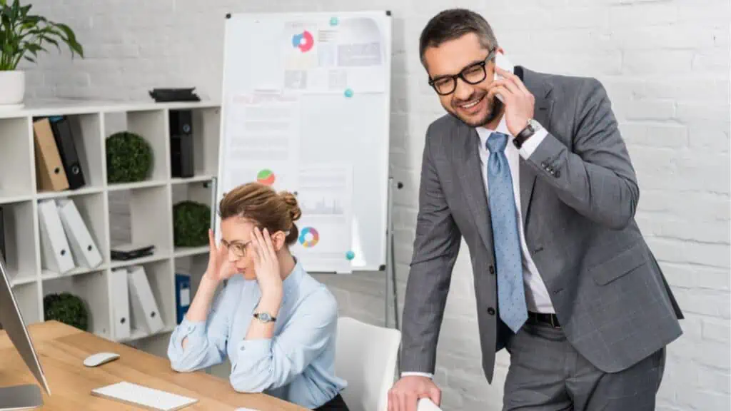 Businessman talking by phone while his annoyed colleague trying to work