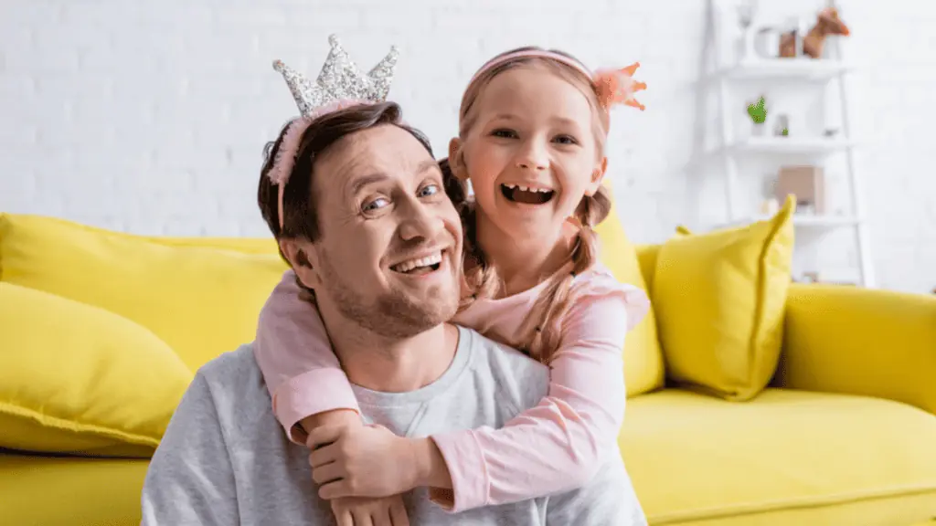 Cheerful father and child in toy crowns laughing at camera