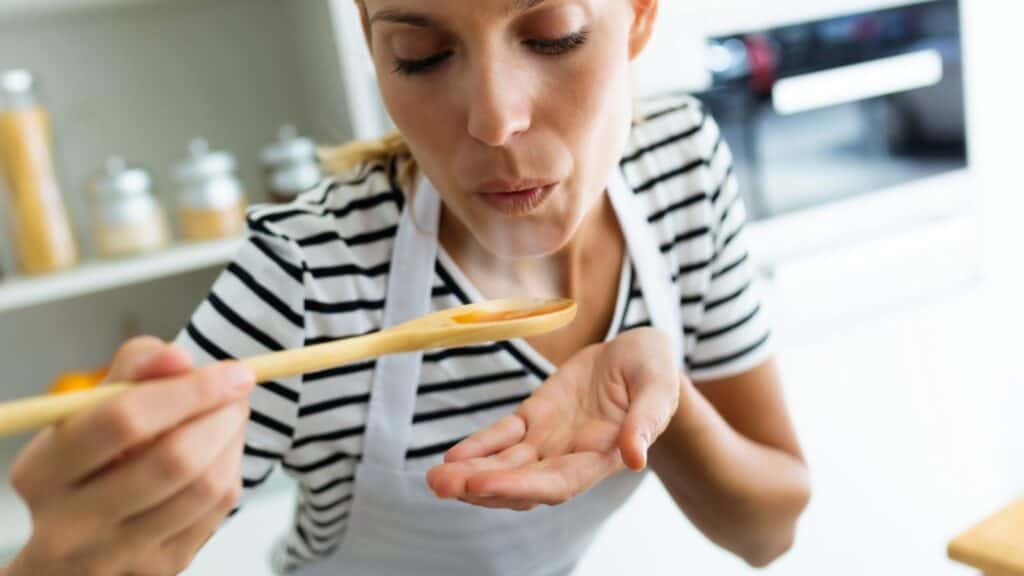 Close up Healthy Young Woman Cooking Blowing Food Wooden Spoon Kitchen