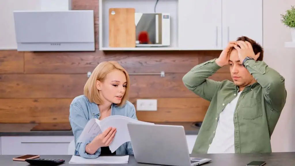 Confused couple doing their accounts at home using laptop