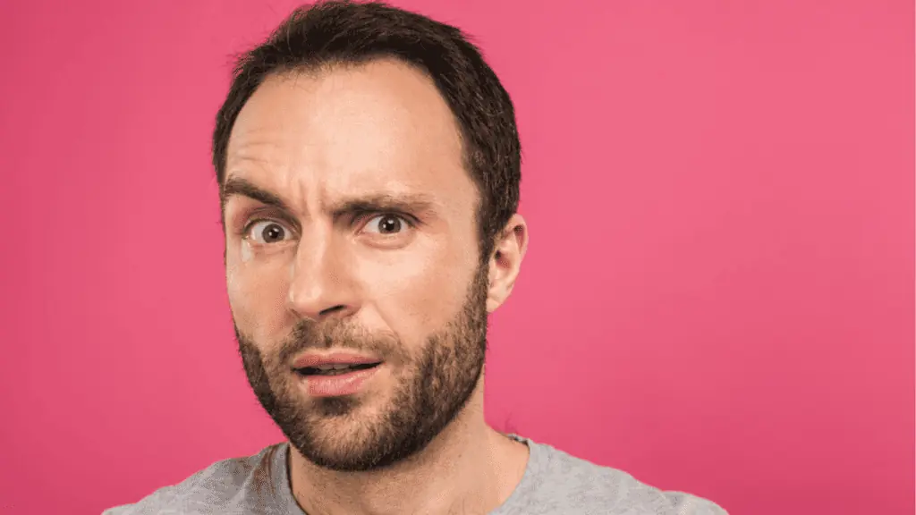 Confused man looking at camera on pink background