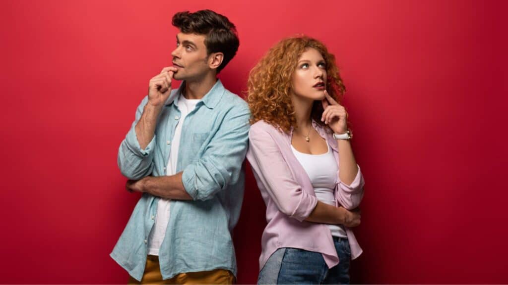 Couple thinking and looking up, isolated on red