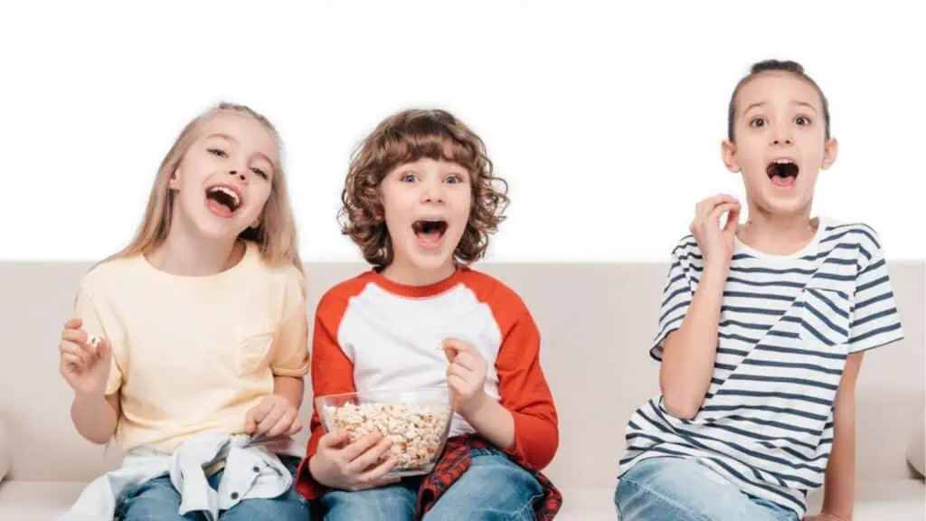 Cute children on couch with popcorn