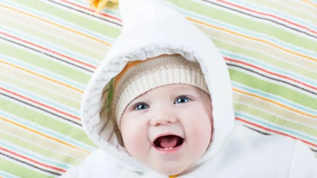 Cute funny laughing baby girl relaxing on a colorful blanket