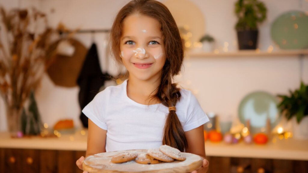 Cute happy girl with cookies on kitchen