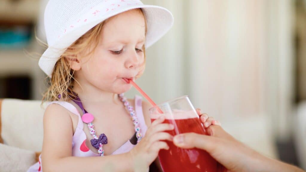 Cute little girl drinking juice in restaurant