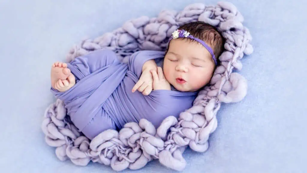 Cute newborn baby wrapped in purple blanked