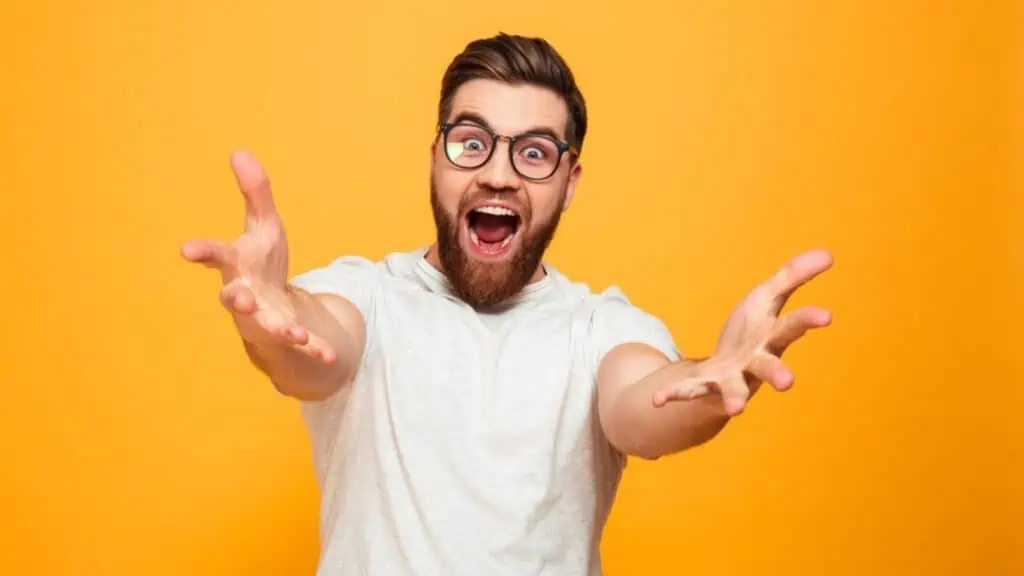 Excited bearded man in glasses on orange background