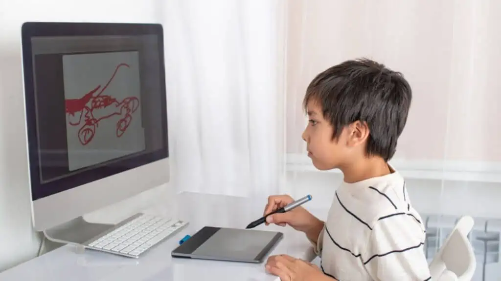 Excited little boy draw on a computer using a tablet in the room