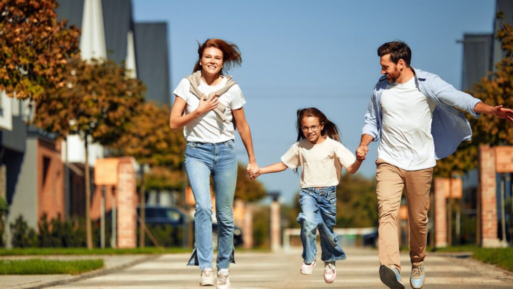 Family with child walking and running holding hands along street