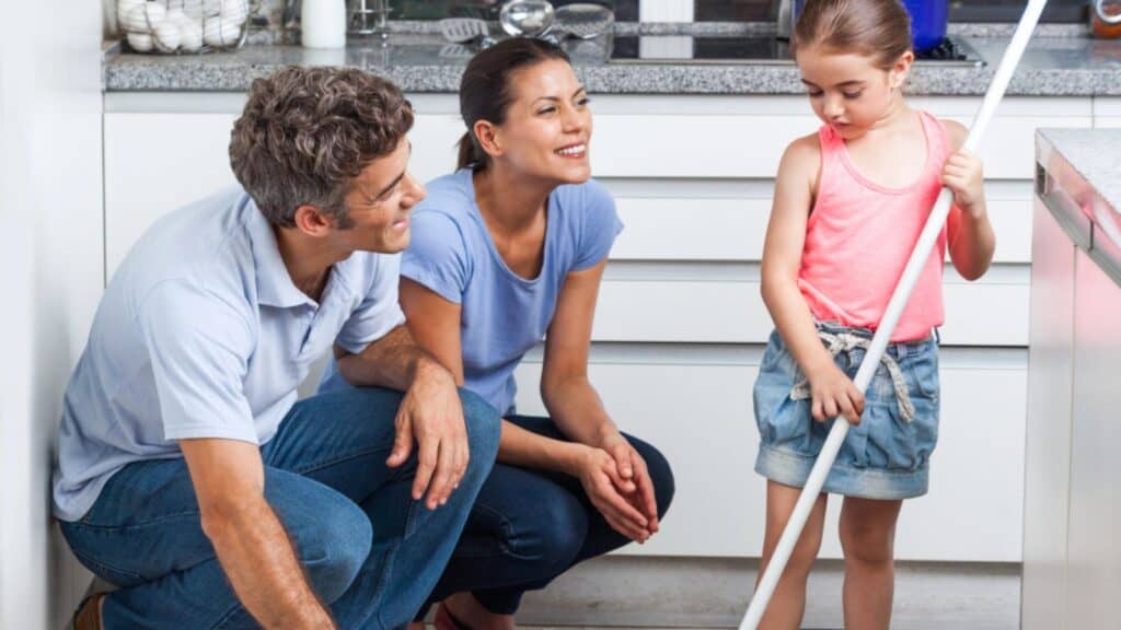 Father, mother and daughter sweeping floor
