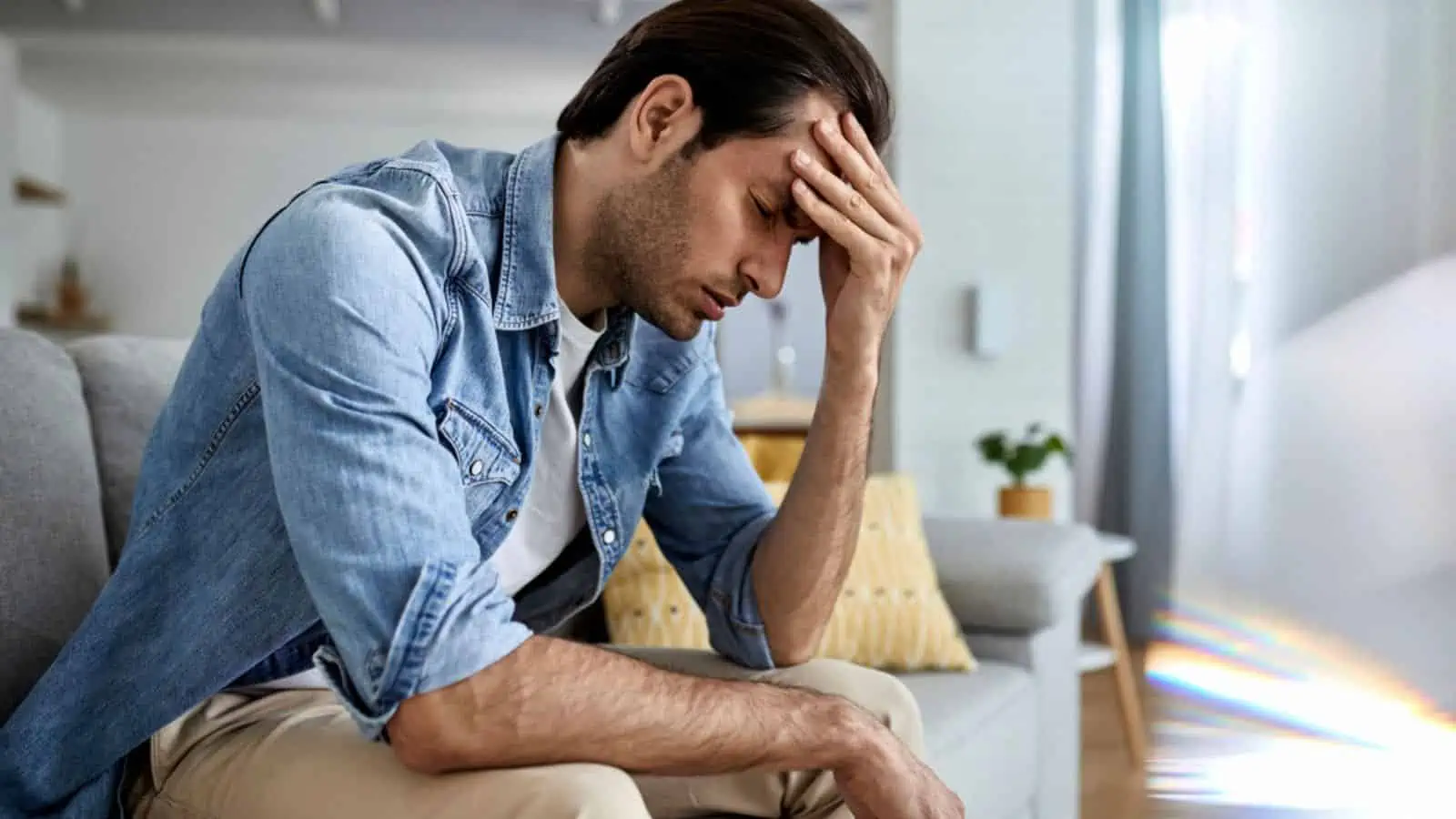 Frustrated man holding his head at home