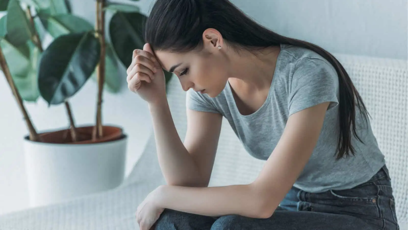 Frustrated sad young woman in depression sitting on couch