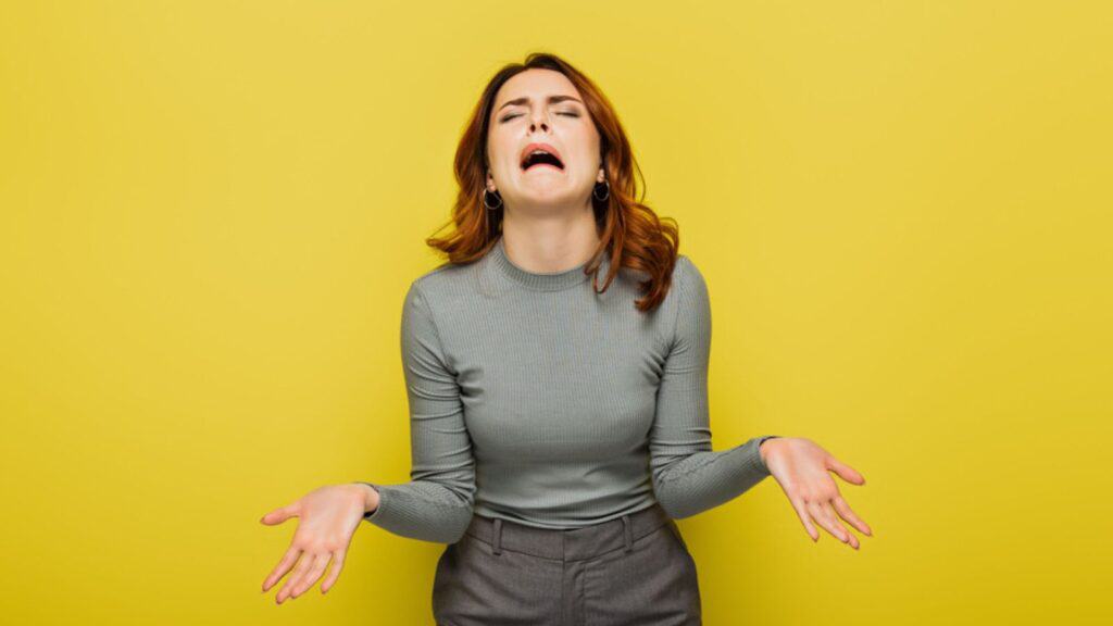 Frustrated woman whining and gesturing isolated on yellow