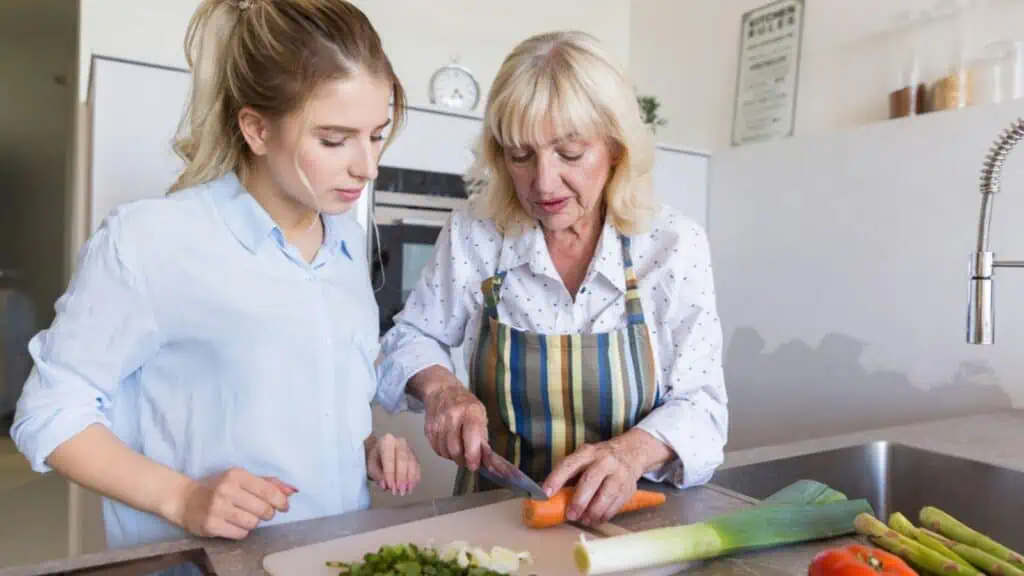 Grandmother teaching her granddaughter how to make a salad