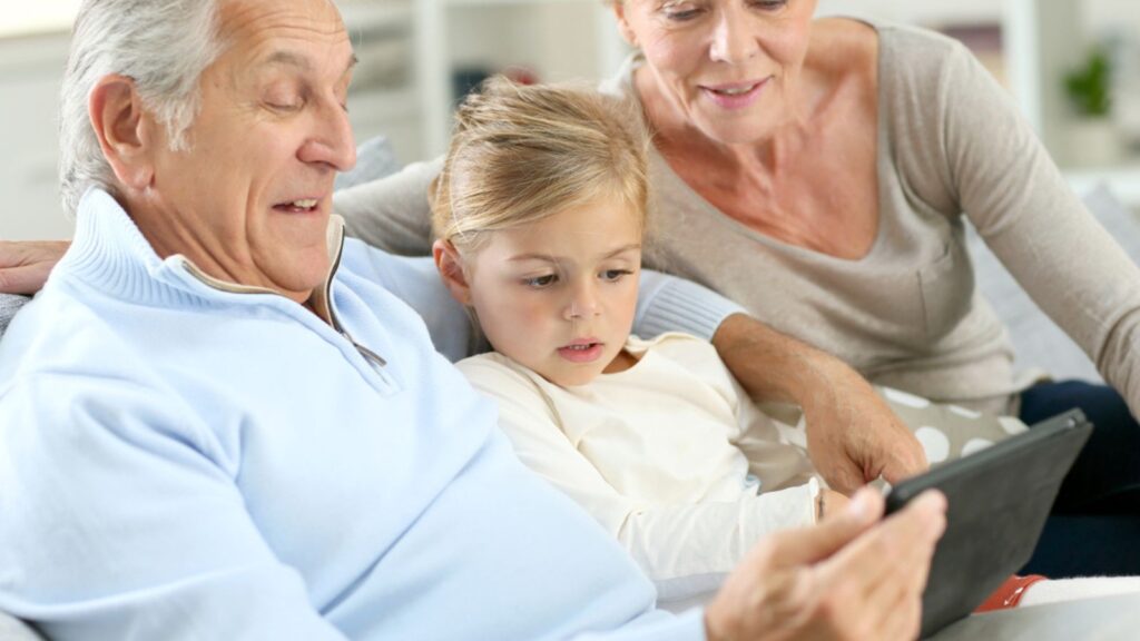 Grandparents with granddaughter using tablet
