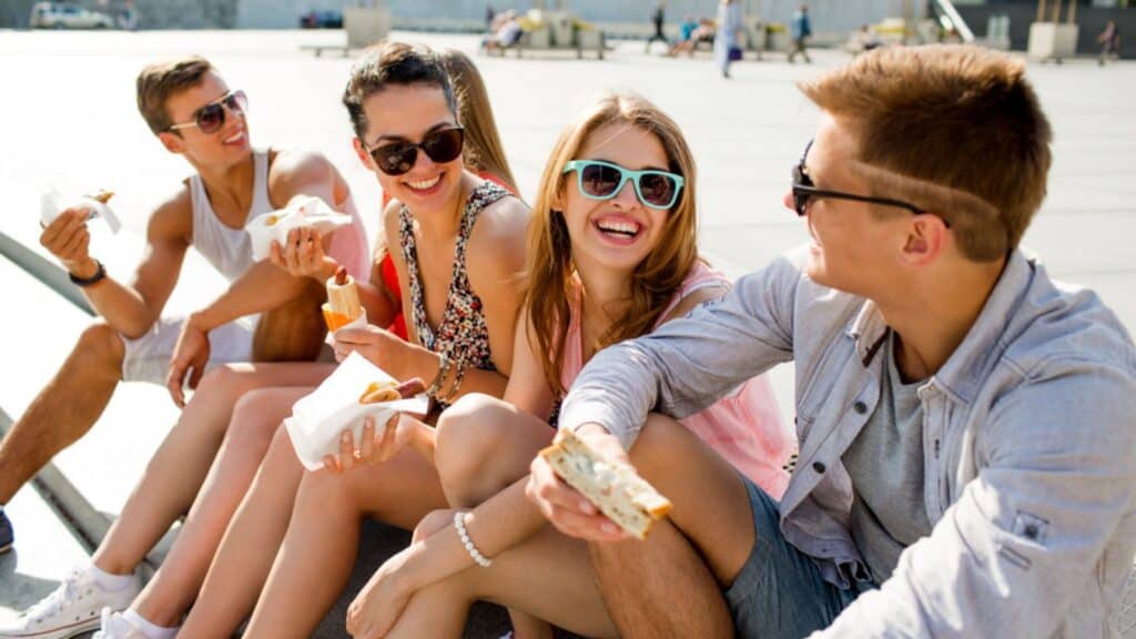 Group of smiling friends sitting on city square