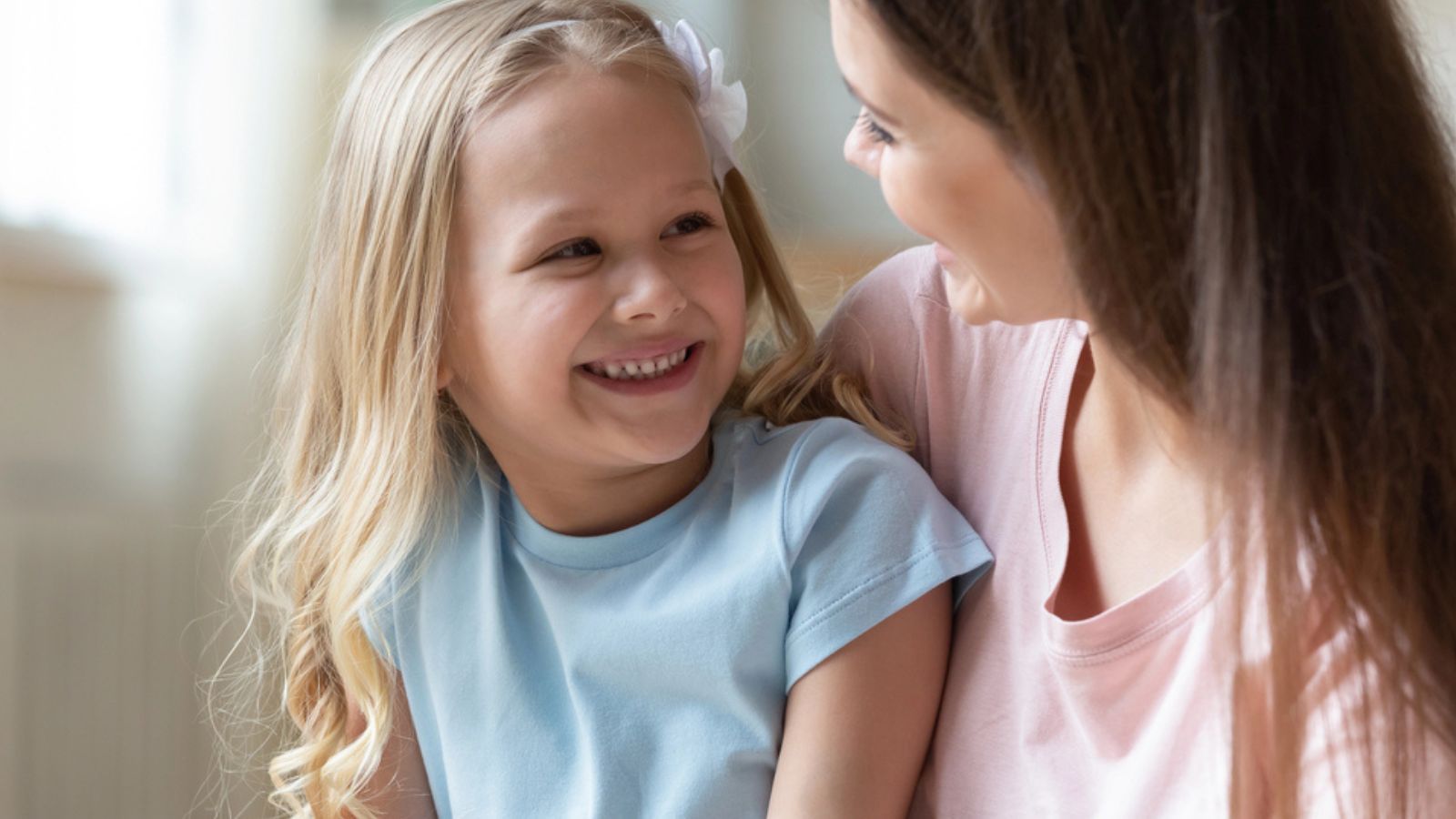 Happy adorable little preschool girl talking with positive mommy