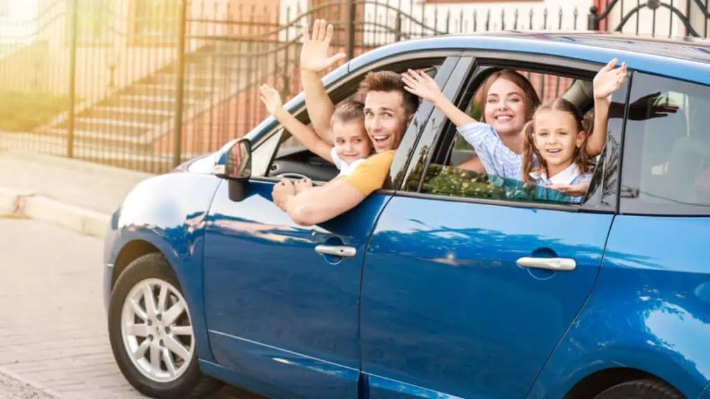 Happy family travelling by a blue car