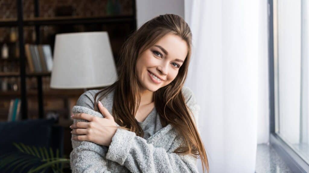 Happy girl hugging herself and looking at camera
