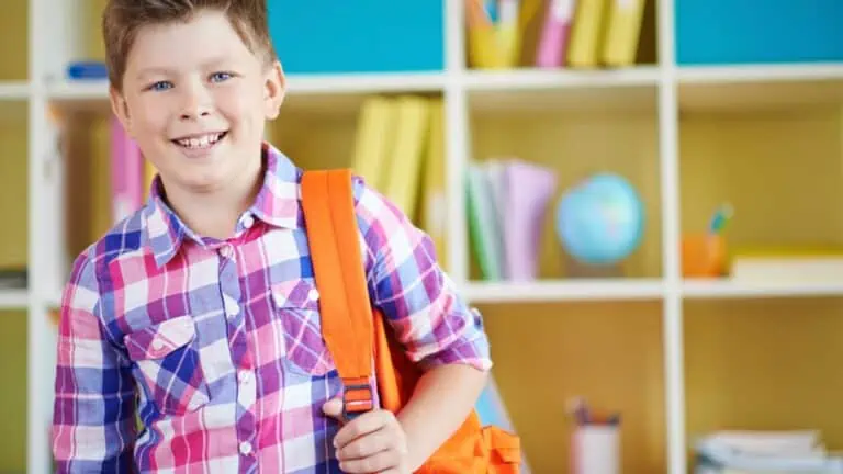Happy kid in school with orange backpack
