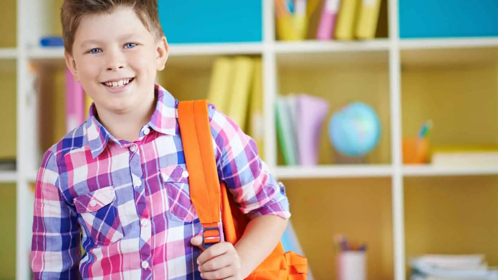 Happy kid in school with orange backpack