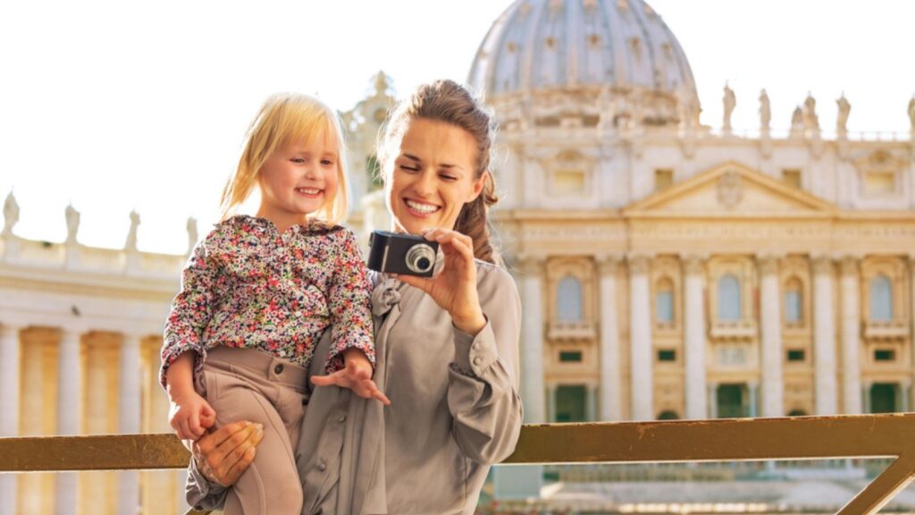 Happy mother and baby girl checking photos in camera in front of Vatican City