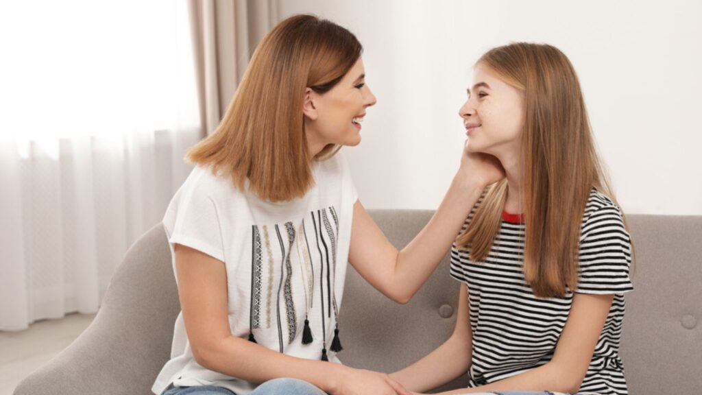 Happy mother talking with her teenager daughter at home