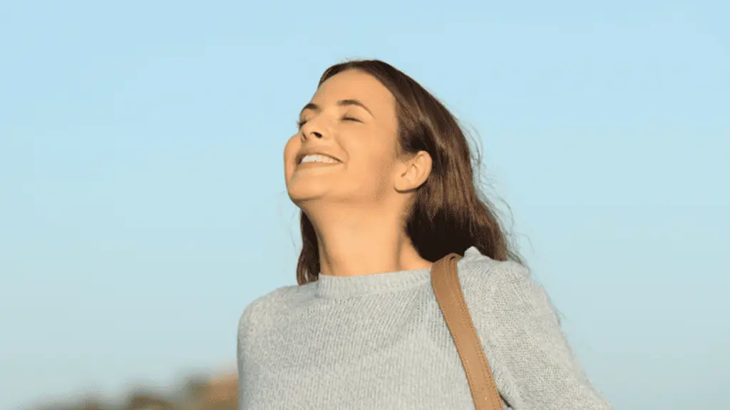 Happy woman breathing fresh air with a blue sky