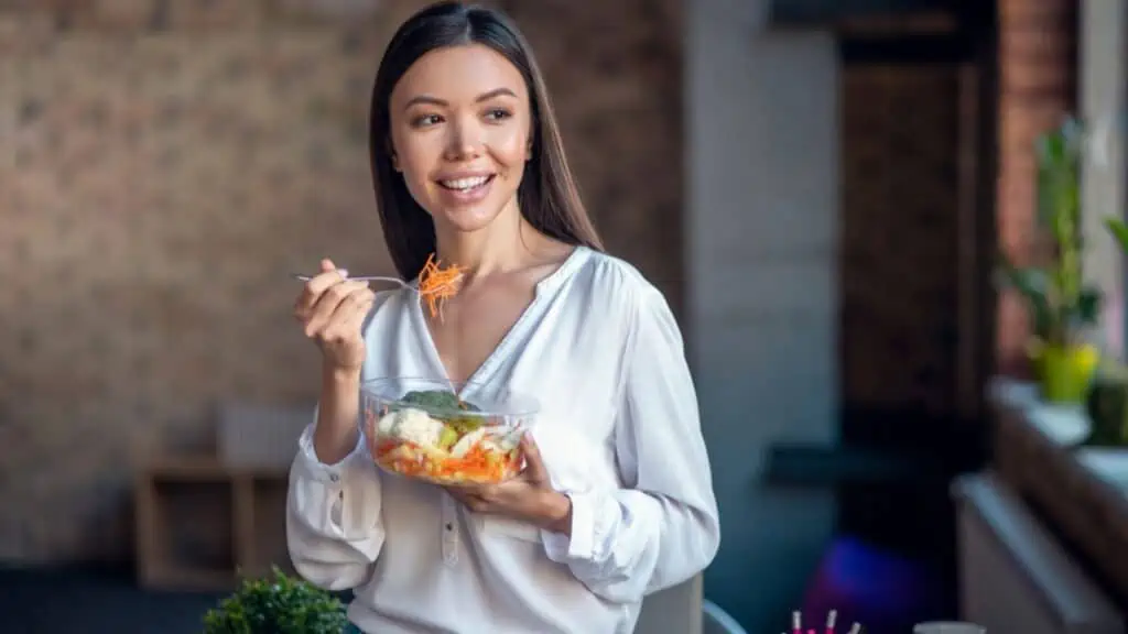 Happy woman eating a vegetable salad