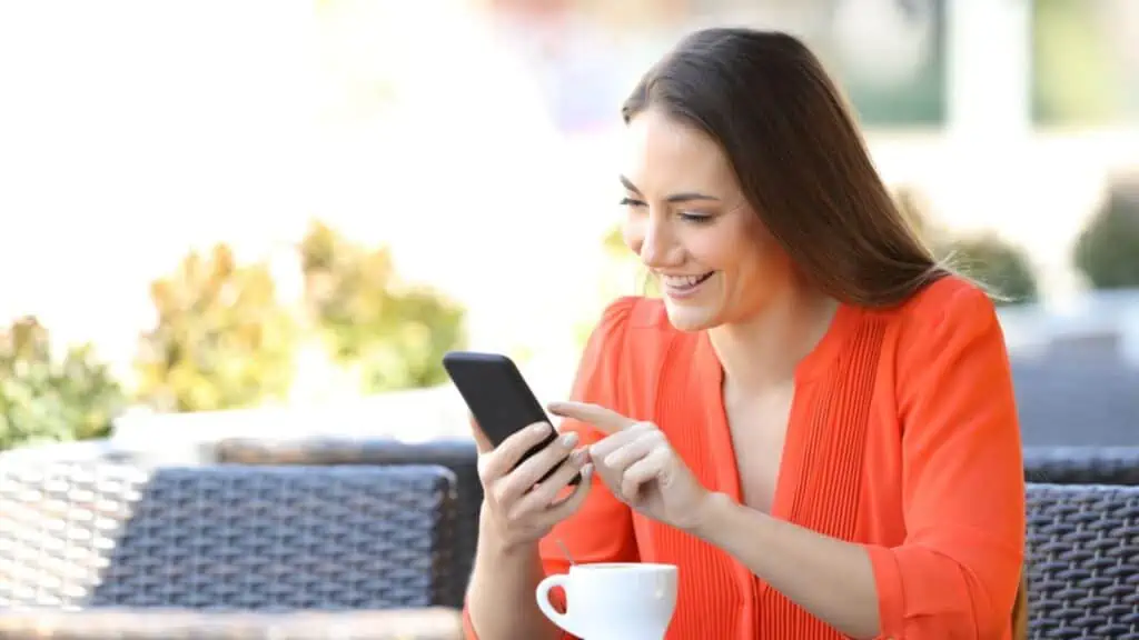 Happy woman is browsing a smart phone in a coffee shop