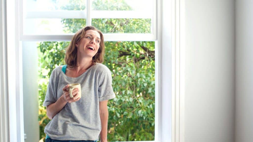 Happy woman laughing with a cup of coffee at home