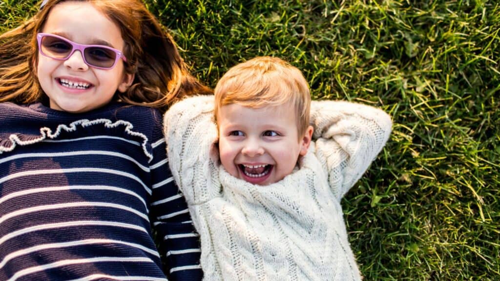 Happy young children laying in grass on sunny day