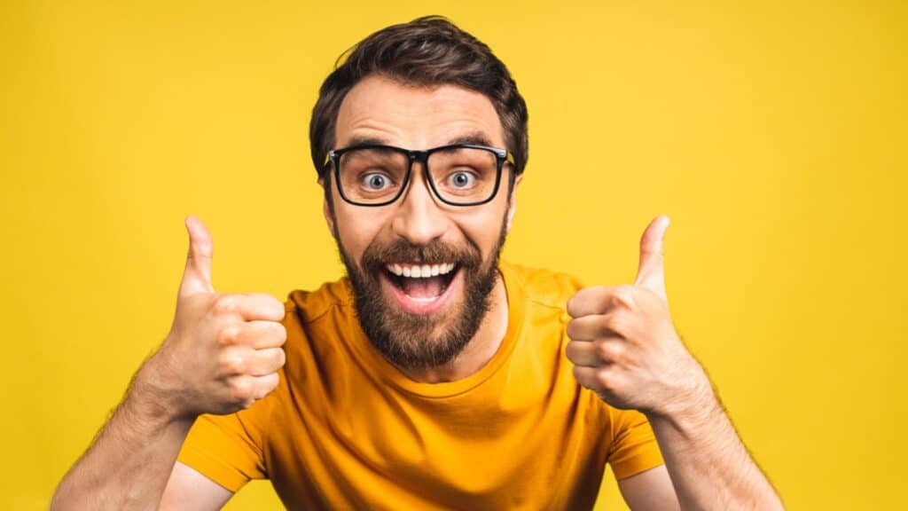 Happy young man thumbs up isolated in yellow