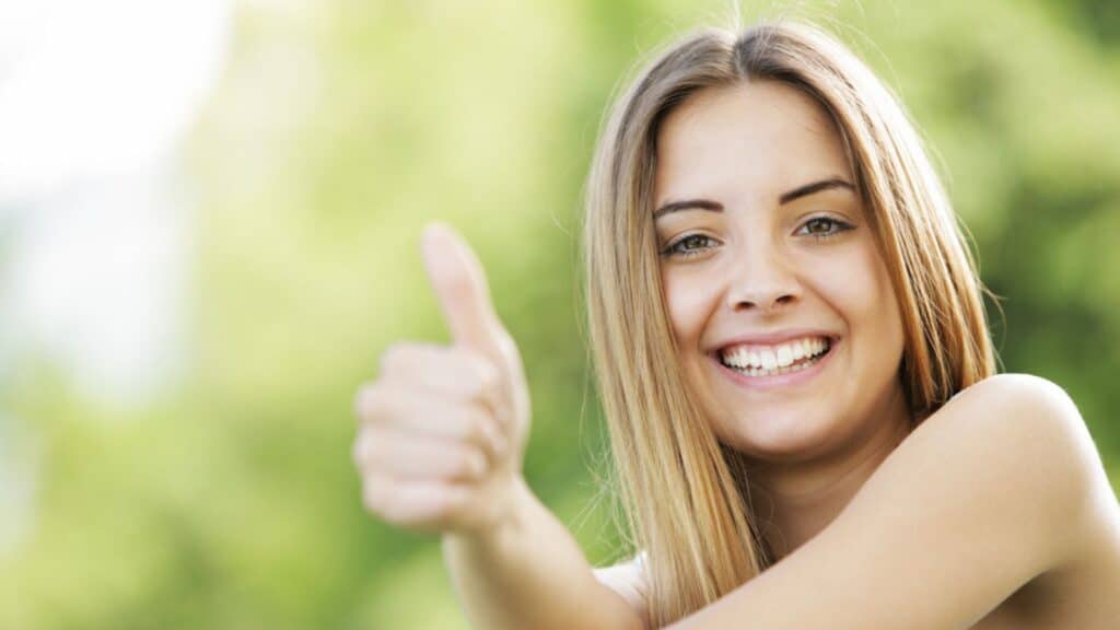 Happy young woman showing thumbs up sign